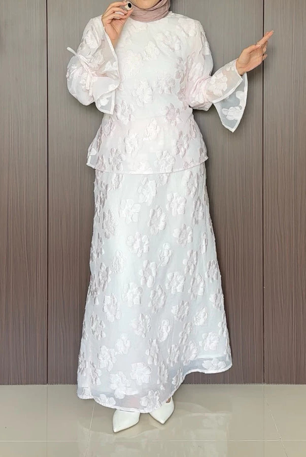 A rose pink floral outfit by Renaette worn by a person against a wooden panel background