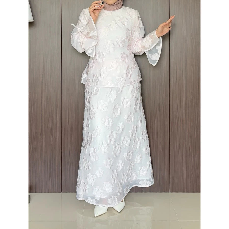 A rose pink floral outfit by Renaette worn by a person against a wooden panel background