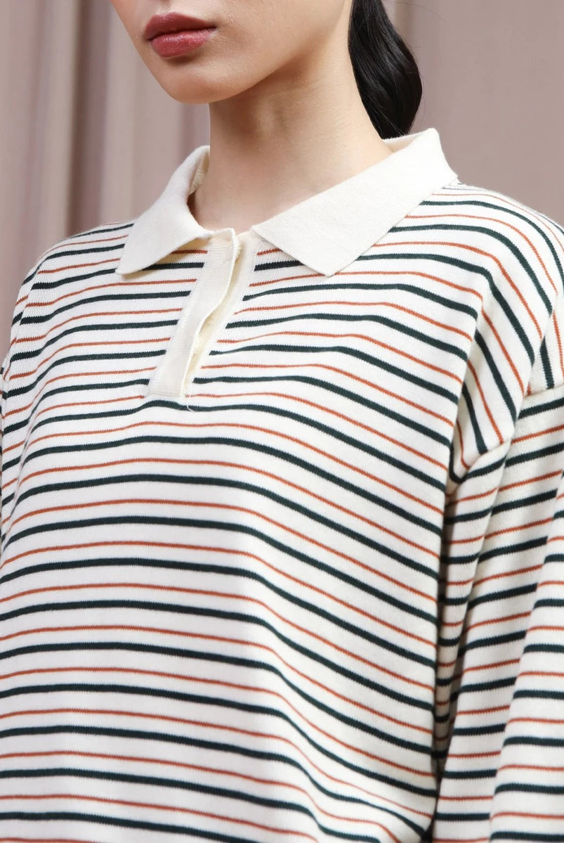 A close-up of a model wearing a long-sleeve polo shirt by Hijabchic with horizontal stripes in green, orange, and black on an off-white base, featuring a solid off-white collar.