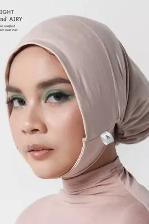 Woman wearing a beige ciput dagu with 'alif' branding on a white background