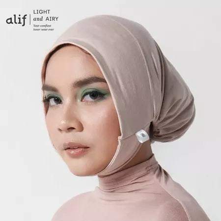 Woman wearing a beige ciput dagu with 'alif' branding on a white background