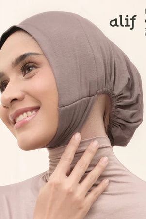 Woman wearing a brown ciput dagu with 'alif' branding on a white background