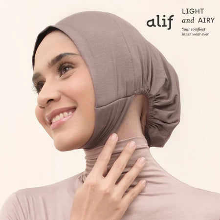 Woman wearing a brown ciput dagu with 'alif' branding on a white background