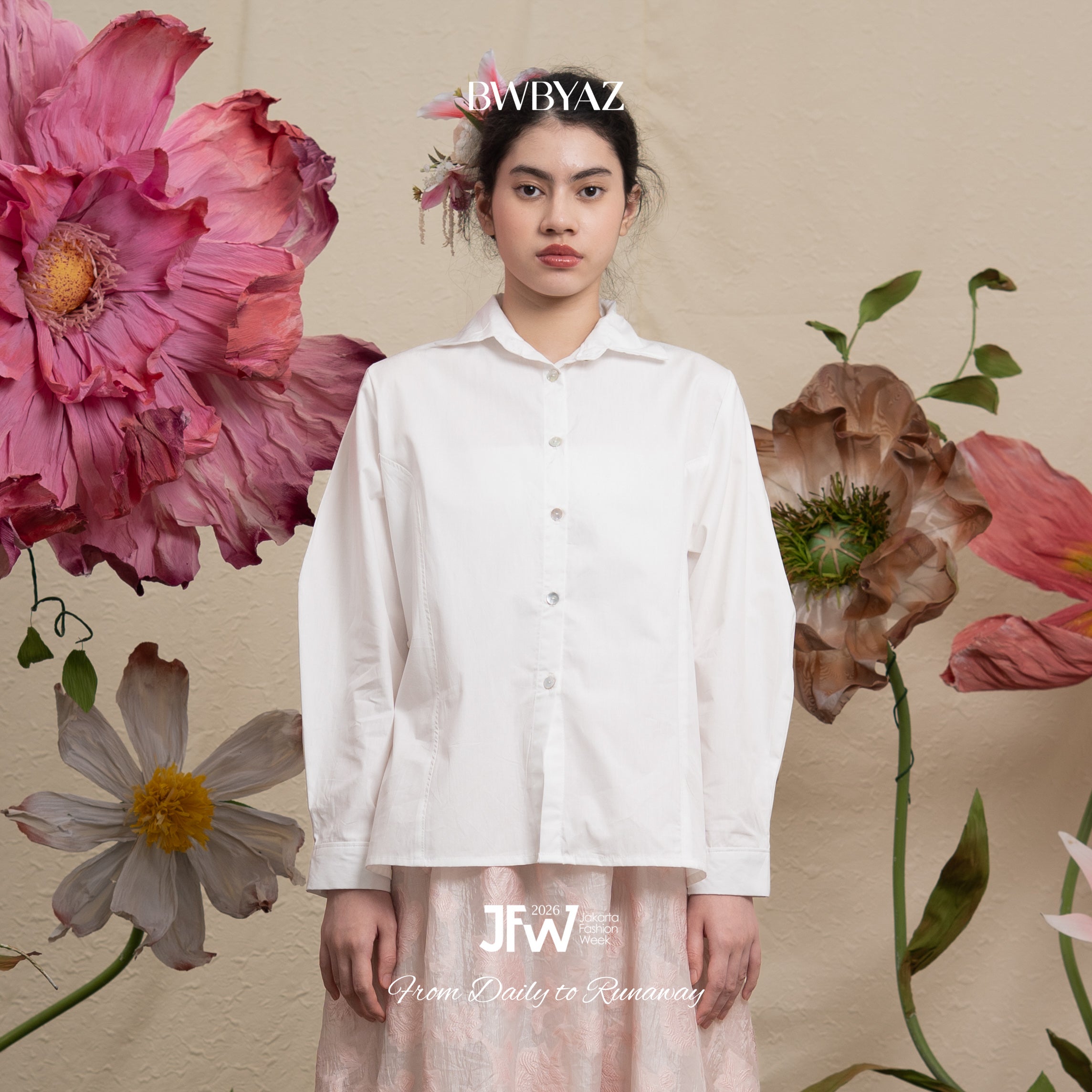 Woman wearing a white shirt with floral decorations and 'BWBYAZ' branding.