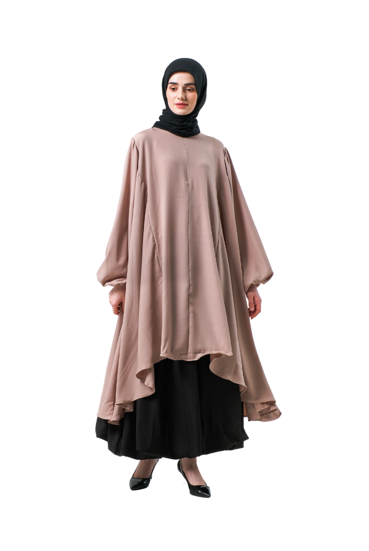A woman wearing a blush pink tunic with a round neckline and long sleeves, paired with a black skirt and a black headscarf.