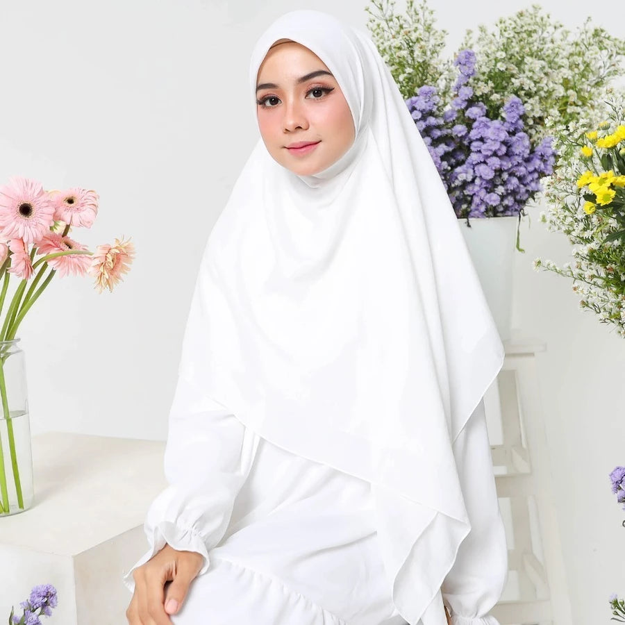 Woman wearing a white square hijab by Lozy Hijab with flowers in the background