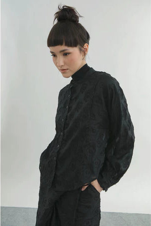 Person wearing a black textured shirt by Yestoday against a plain background