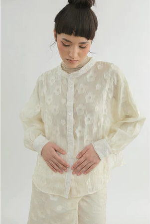 Person wearing a light-colored shirt by Yestoday with a subtle pattern on a white background