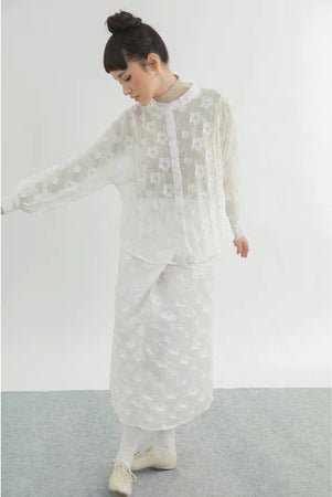 Person wearing a white floral shirt by Yestoday against a plain background