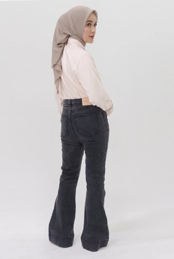 Woman wearing a beige hijab, light-colored top, and dark flared denim pants by Jenna & Kaia on a white background
Seorang wanita mengenakan hijab krem, atasan berwarna terang, dan celana denim melebar berwarna gelap dari Jenna & Kaia dengan latar belakang putih