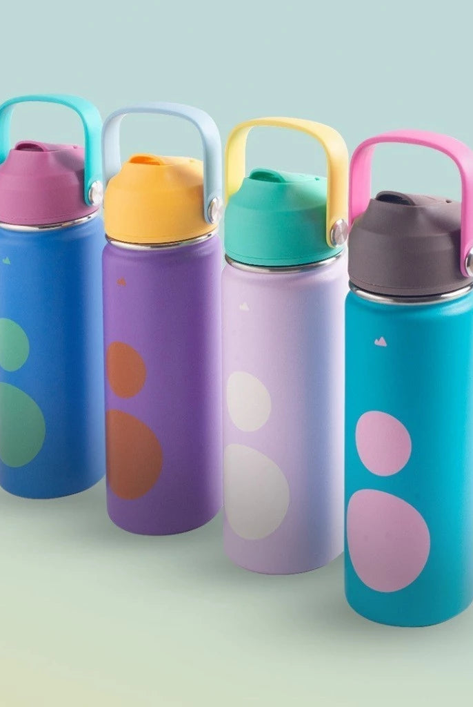 Four colorful water bottles with polka dot designs on a light green background