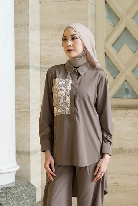 Woman wearing a brown outfit with floral embroidery by Tunique in an indoor setting