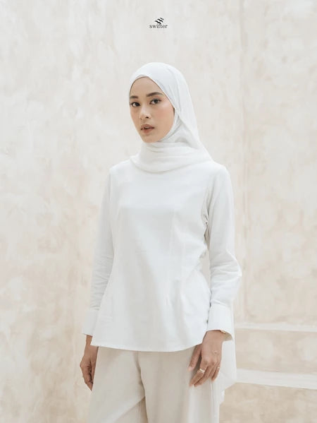 Woman wearing a white hijab and blouse by Swifter against a plain background