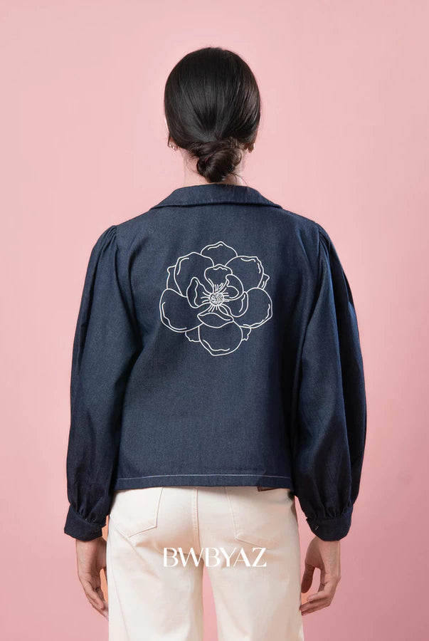 Person wearing a indigo blue jacket by BWBYAZ with a floral design on the back against a pink background