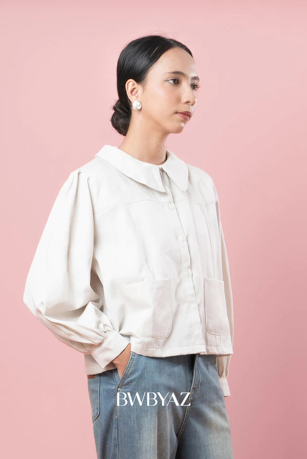 Person wearing a vanilla-colored jacket and jeans against a pink background with 'BWBYAZ' branding.