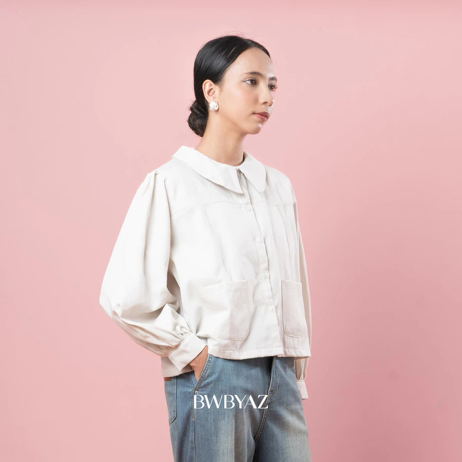 Person wearing a vanilla-colored jacket and jeans against a pink background with 'BWBYAZ' branding.