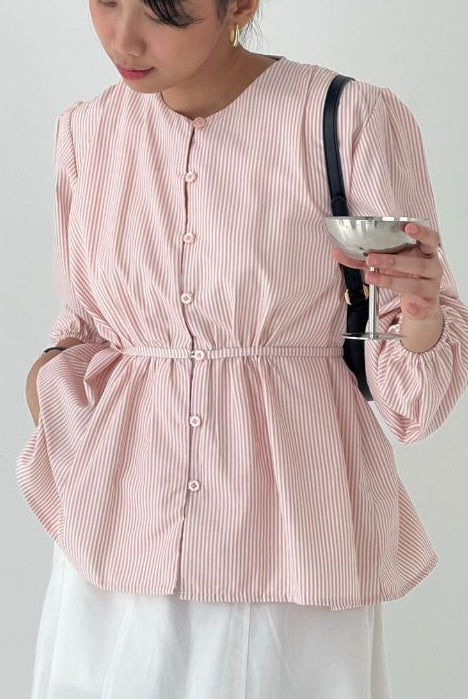Person wearing a pink striped blouse by BWBYAZ holding a glass against a plain background