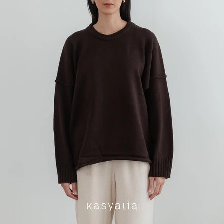 Person wearing a dark brown oversized sweater and beige pants on a light gray background with 'kasyalia' branding.