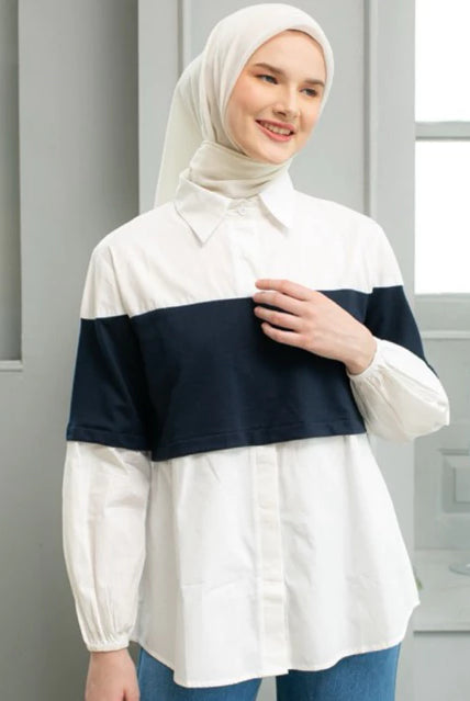 Woman wearing a white and navy shirt by Casa Elana with a hijab in a room with windows and candles.