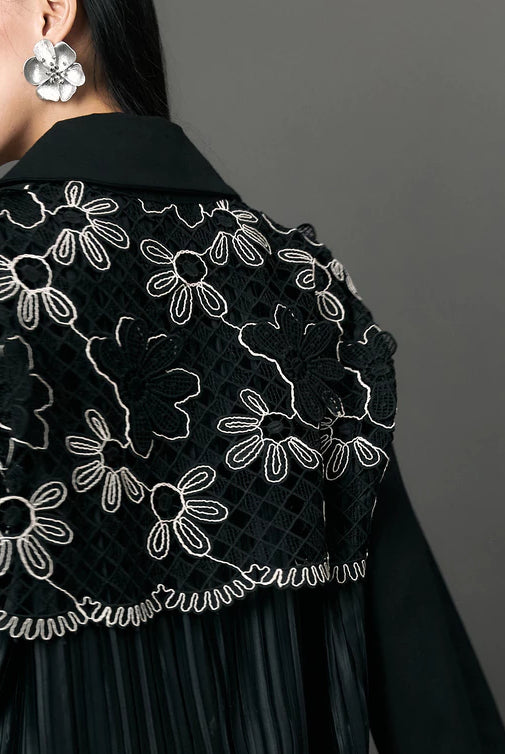 Black embroidered outerwear by Studio Tui with white floral patterns on a plain background