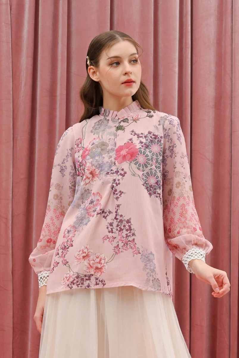 Woman wearing a floral pink blouse by Kasa Heritage against a pink curtain background