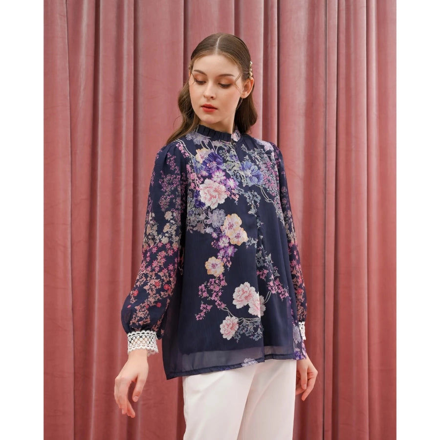 Woman wearing a floral navy blouse by Kasa Heritage against a pink curtain background