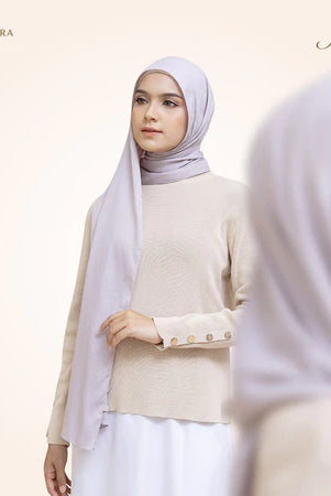 A woman wearing a light purple pashmina viscose draped around her head, with the brand 'Puru Kambera' visible on the scarf.