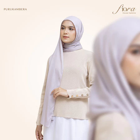 A woman wearing a light purple pashmina viscose draped around her head, with the brand 'Puru Kambera' visible on the scarf.