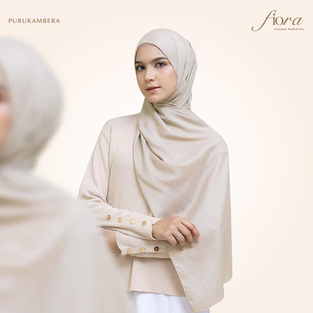 A woman wearing a light beige pashmina viscose draped around her head, with the brand 'Puru Kambera' visible on the scarf.