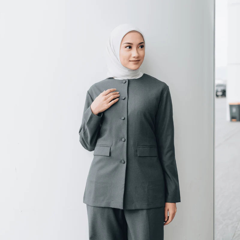 Person wearing a dark gray blazer from Atala Scarves with a hijab against a white background