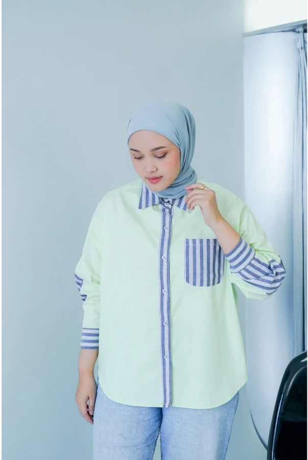Woman wearing a light green shirt with striped sleeves and a matching hijab against a white background