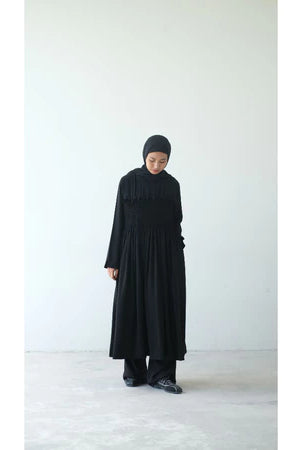Person wearing a long black dress and black headscarf by Rashawl on a white background
