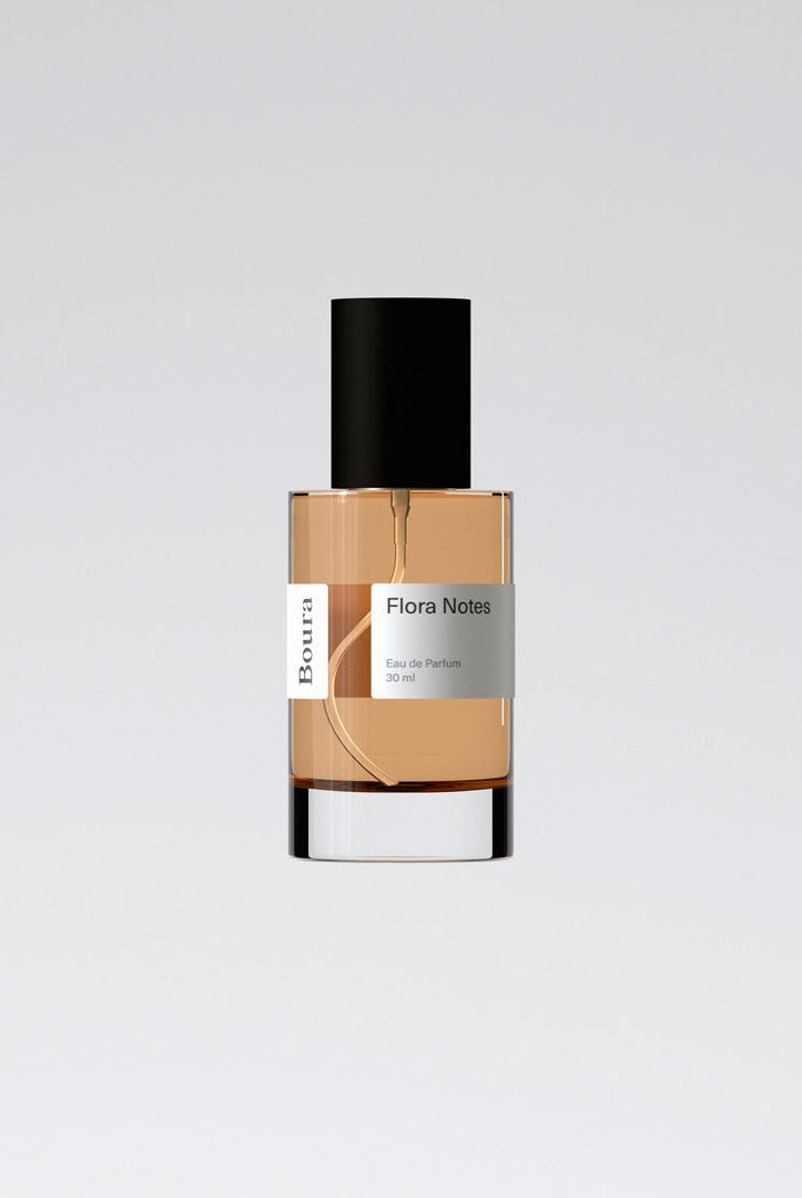 A bottle of 'Flora Notes' perfume with a beige liquid and black cap from Boura, presented against a white background.