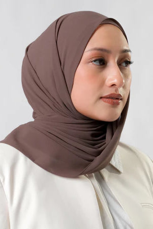 Woman wearing a brown pashmina hijab by Tantri Namirah Official against a white background
