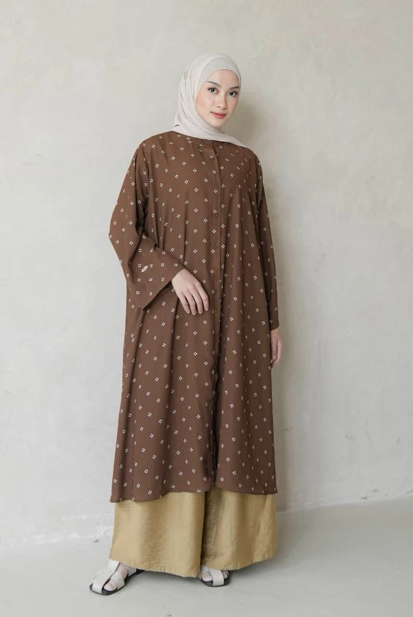 Woman wearing a brown tunic with white patterns by Mistyvori against a plain background
Seorang wanita yang mengenakan tunik cokelat dengan motif putih dari Mistyvori di atas latar belakang polos