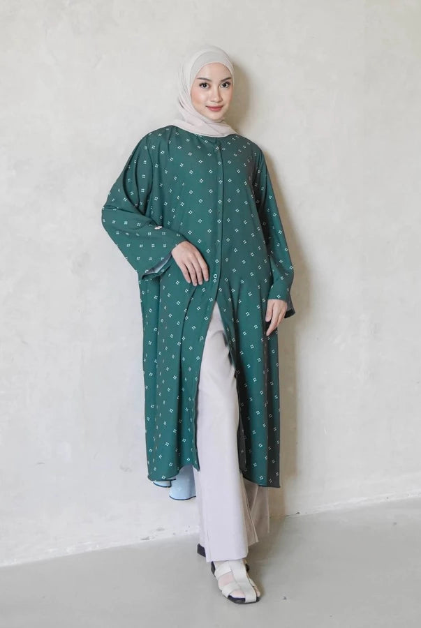 Woman wearing a emerald green tunics with white pattern by Mistyvori against a plain background
Seorang wanita mengenakan tunik berwarna hijau zamrud dengan motif putih dari Mistyvori di atas latar belakang polos