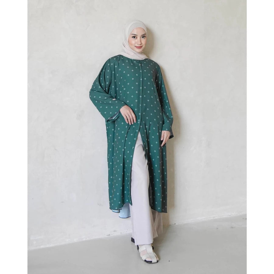 Woman wearing a emerald green tunics with white pattern by Mistyvori against a plain background
Seorang wanita mengenakan tunik berwarna hijau zamrud dengan motif putih dari Mistyvori di atas latar belakang polos