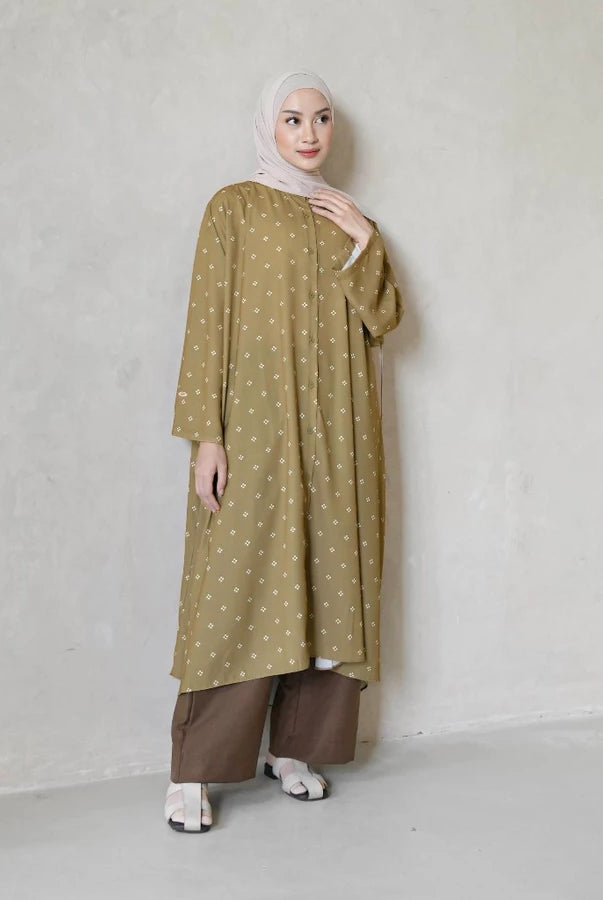 Woman wearing a long butter yellow tunic with white patterns by Mistyvori and brown pants against a plain background
Seorang wanita mengenakan tunik panjang berwarna kuning mentega dengan motif putih dari Mistyvori dan celana cokelat, dengan latar belakang polos