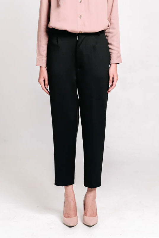 Person wearing black ankle pants from Atala Scarves and a light pink shirt on a white background