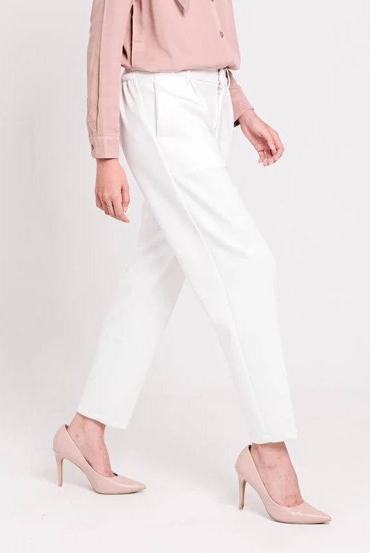Person wearing a pink blouse, broken white ankle pants from Atala Scarves, and pink high heels on a white background
