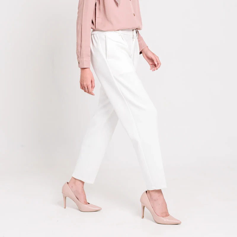 Person wearing a pink blouse, broken white ankle pants from Atala Scarves, and pink high heels on a white background