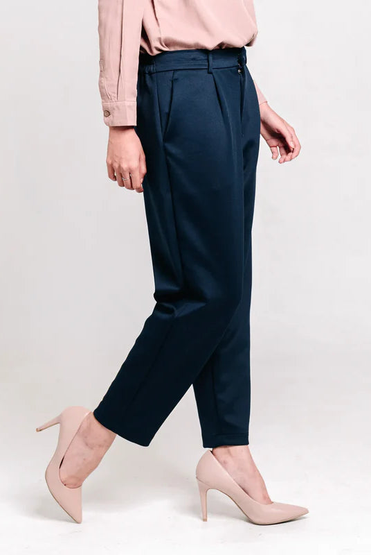 Person wearing navy ankle pants from Atala Scarves and pink shoes on a light gray background