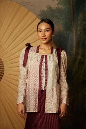 Woman wearing a traditional kebaya by Kartinis Label with a decorative and painting in the background