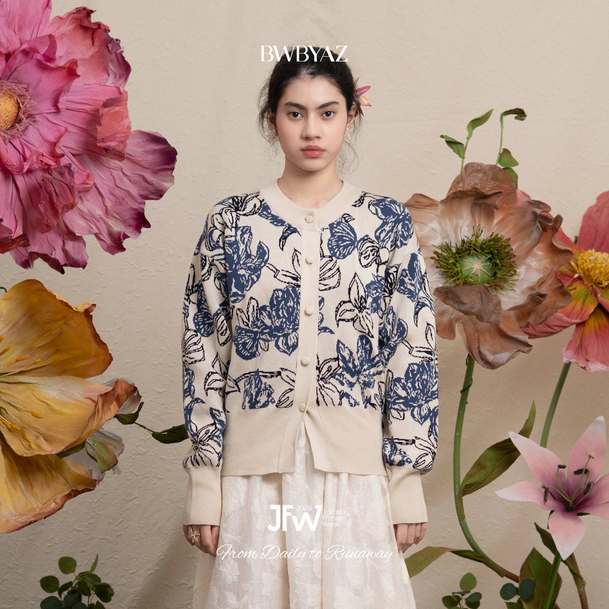 Woman wearing a blue floral patterned cardigans with large flowers in the background, featuring the brand 'BWBYAZ'.