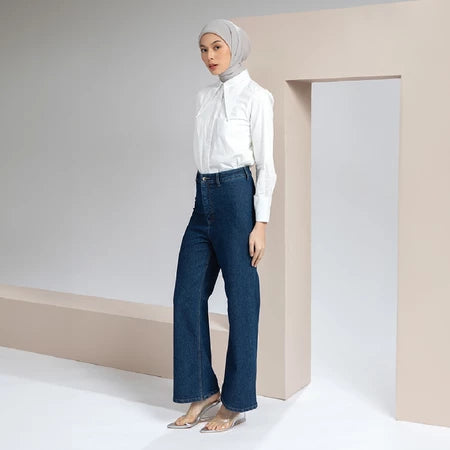 Woman wearing a white blouse and blue jeans with a hijab in a minimalistic setting.
Seorang wanita yang mengenakan blus putih dan celana denim biru serta hijab, dalam latar belakang yang minimalis.