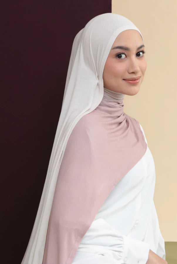 Woman wearing a white hijab shawl by Lozy Hijab and pink top against a two-tone background