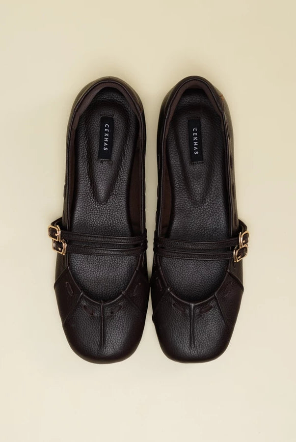 A pair of brown leather Mary Jane flatshoes with gold-tone buckle straps, shown from a top-down view on a light beige background. The brand name 'Cekhas' is visible on the insole of each shoe.