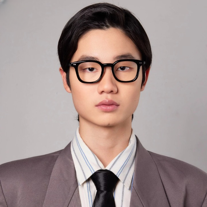 A person wearing a suit and black eyeglasses with round frames from HSF Eyewear.