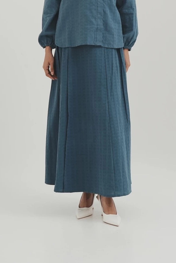 Person wearing a teal outfit with a long denim skirt by Tunique on a light gray background