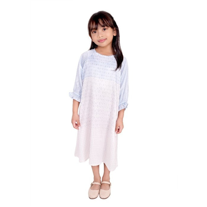 A girl wearing a sky blue tunic with long sleeves and a round neckline.
Seorang anak wanita memakai tunik berwarna biru langit berlengan panjang dan kerah bulat.